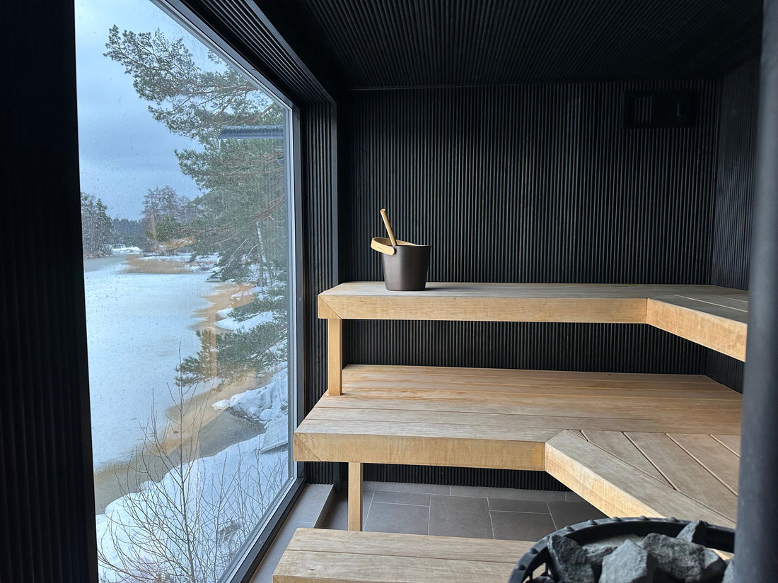 Interior of a Finnish sauna with wooden benches, a sauna stove, and a window overlooking the Stockholm archipelago.